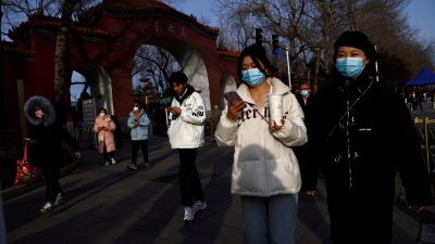 2月14日在中国北京的大街上，民众戴著口罩预防新冠肺炎。（图取自路透社档案照）