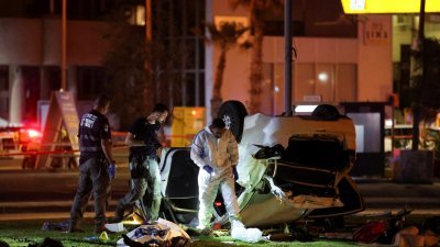以色列特拉维夫周五发生汽车冲撞袭击事件，肇事汽车翻倒在路旁的公园草地上，执法人员在现场搜证。（图取自路透社）