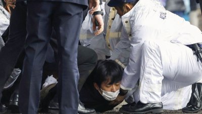 日本首相岸田文雄周六在和歌山市街头助选时遭人丢掷爆裂物，24岁嫌犯木村隆二（中）当场被逮。（图取自共同社/路透社）