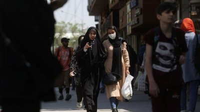伊朗严格要求女性戴头巾，上周六在首都德黑兰街头，年轻女子配戴头巾走过马路。（图取自WANA/路透社）