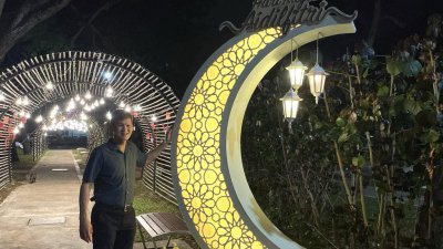 王耶宗与“竹子隧道”前的新月装饰拍照合影。 
