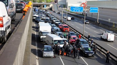 德国的气候示威者周一将手黏在首都柏林的高速公路，造成严重塞车，警方到场将他们赶走。（图取自路透社）
