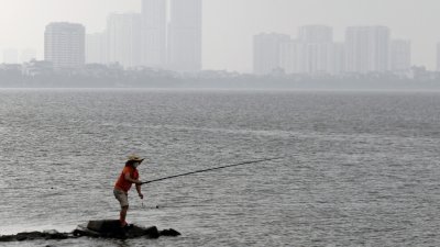 图为越南河内一名男子上周二在西湖钓鱼。（图取自法新社）