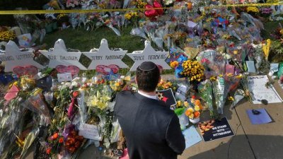 2018年10月31日，宾州匹兹堡生命树犹太教堂发生枪击事件后，一名男子在教堂外的临时纪念处前祈祷。（图取自路透社档案照）