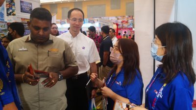 拉维古玛（左起）在王振添等人陪同下，参观位于Johor MATTA Fair新山站，并聆听旅行社工作人员介绍旅游配套。