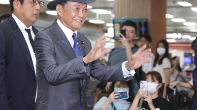 前日本首相暨自民党副总裁麻生太郎（左2）率团访问台湾，周一搭机抵达台北松山机场，向现场民众挥手致意。（图取自中央社）