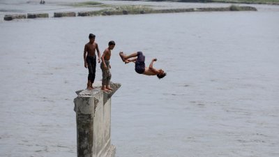 巴基斯坦白沙瓦郊区纳古曼7月27日，男孩们在炎热的天气下跳入纳古曼河洗澡纳凉。（图取自路透社）