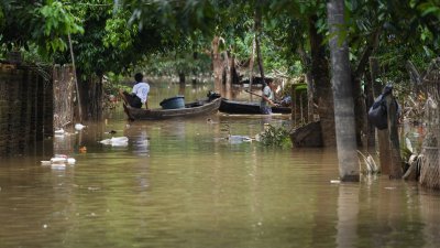 周五在缅甸孟邦比林镇，被洪水淹没的街道上，居民利用船撤离家园。（图取自法新社）
