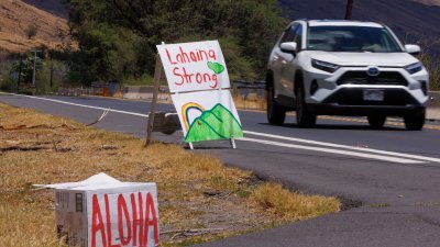民众在夏威夷毛伊岛的一条高速公路边，竖起了标志为被大火蹂躏的拉海纳镇打气。（图取自路透社）