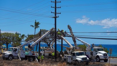 电力公司的工人周二在夏威夷毛伊岛遭大火蹂躏的拉海纳镇，修复路边的电线设施。（图取自路透社）