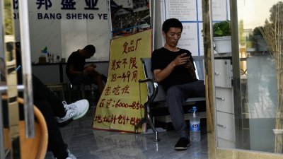 在中国北京劳动力市场的一栋大楼内，一名男子正在查看手机。（图取自法新社）