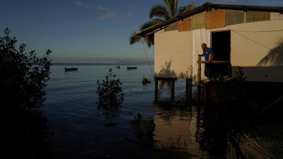 斐济维瓦图洛亚村的居民，在涨潮时看著自家周围的海水泛滥。斐济是一个由数百个岛屿组成的群岛，2014年成为首个因海平面上升而搬迁社区的太平洋岛国。（图取自路透社）