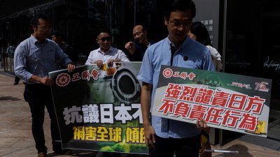 在日本宣布本周四会启动福岛核污水排海后，香港周二有示威者手持手持标语牌抗议。（图取自路透社）