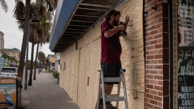 在飓风“伊达利亚”来袭之前，美国佛罗里达州克利尔沃特海滩附近可见有民众用木板将商店封住，免受飓风破坏。（图取自路透社）