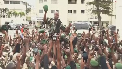 加蓬24频道周三拍摄的视频截图显示，卫队指挥官布里斯·奥利吉·恩圭马（中）被数百名士兵高举，选择他为领导人。（图取自法新社）
