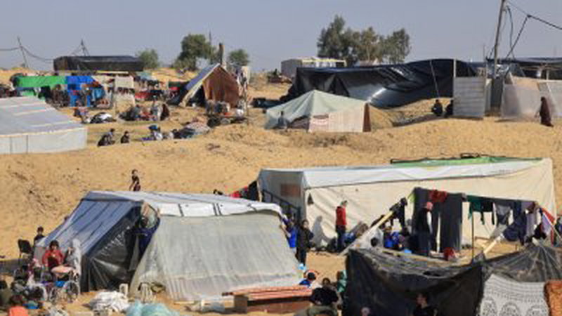 从汗尤尼斯逃离的巴勒斯坦平民周一坐在拉法一处营地的临时避难所外。世卫官员表示，由于加沙许多居民无法获得清洁水和卫生设施，他们担心重大疾病的爆发。（图取自法新社）