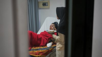 马拉皮火山喷发的幸存者蒂塔，在西苏门答腊省巴东班让市一家医院接受治疗.她的面部明显烧伤，手掌也被捆上纱布。（图取自路透社）