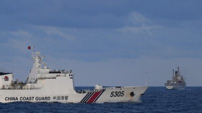一艘中国海警船周日在有主权争议的南中国海海域附近，驶过一艘菲律宾船只（右）。（图取自法新社）
