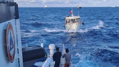 一艘菲律宾海岸警卫队船只周日在南中国海，拖走一艘遭中国海警船水炮破坏的菲律宾补给船。（图取自菲律宾海岸警卫队/路透社）