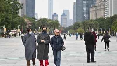 寒潮天气持续影响中国广东省广州市，市民出门都穿上御寒衣服保暖。（图取自中新社）