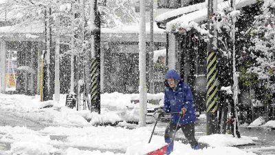 新潟县长冈市的居民，在清除人行道上的积雪。（图取自网络）
