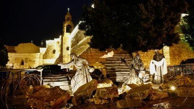 在以色列占领的约旦河西岸伯利恒马槽广场上，圣诞教堂外展示了一个圣诞装置，耶稣诞生场景改成瓦砾堆和铁丝网，而不是马厩。（图取自路透社）