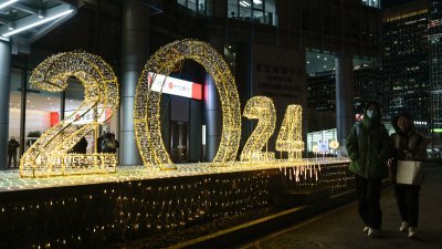 在中国首都北京，民众走过一个“2024”的新年灯光装置。（图取自法新社）