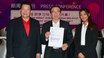 杨安山（左起）、王鸿财和乌玛展示报案书，要求警方以煽动法令调查《每日新闻》和《新海峡时报》。