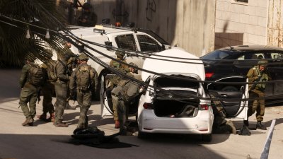 图为周四在约旦河西岸希伯伦，多名以色列军人在检查一辆汽车，气氛紧张。该车子据称被巴勒斯坦人用来对基亚特阿尔巴定居点附近的部队进行袭击。（图取自法新社）