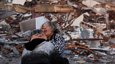 强烈地震破坏了家园，伤心的哈塔伊省灾民相拥痛哭。（图取自路透社）