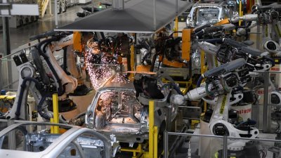 位于浙江宁波中国国产新能源车型生产基地，焊装机器人对车辆框架进行焊装。（图取自中新社）