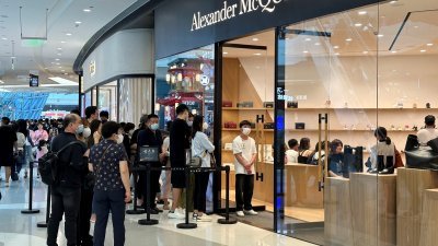 1月25日，在中国海南省三亚市的三亚国际免税购物中心，人们排队等候进入Alexander McQueen商店。（图取自路透社）