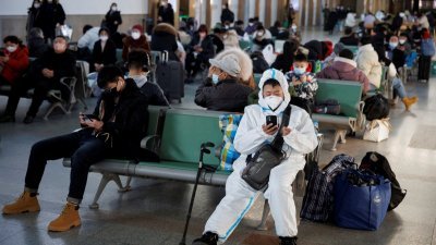 1月20日，一名身穿防护服的人坐在北京火车站。（图取自路透社档案照）