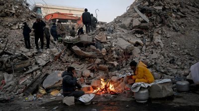 在土耳其卡赫拉曼马拉什，救援队周日继续搜寻受害者和幸存者，亲属们则在倒塌建筑物的废墟前围著火取暖等候消息。（图取自法新社）