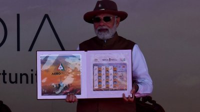 印度总理莫迪在班加罗尔Yelahanka空军基地举行的2023年印度航空展开幕式上展示纪念邮票。（图取自路透社）