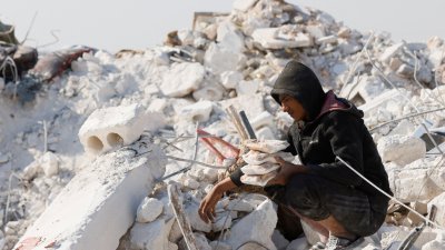 在叙利亚伊德利卜省叛军控制区，一名男子周二从地震废墟中找到食物。（图取自路透社）