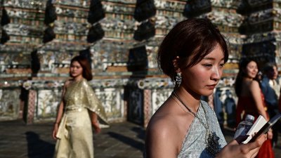 图为身著租来的泰国传统服装的旅客，在曼谷知名景点郑王庙前摆姿势拍照留念。（法新社档案照）
