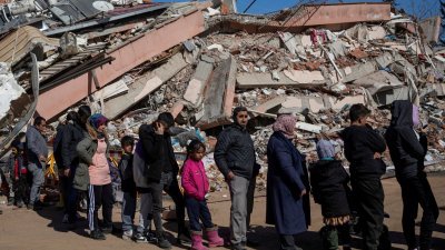 土耳其卡赫拉曼马拉什省的地震灾民，周四在废墟中排队领取免费食物。（图取自路透社）