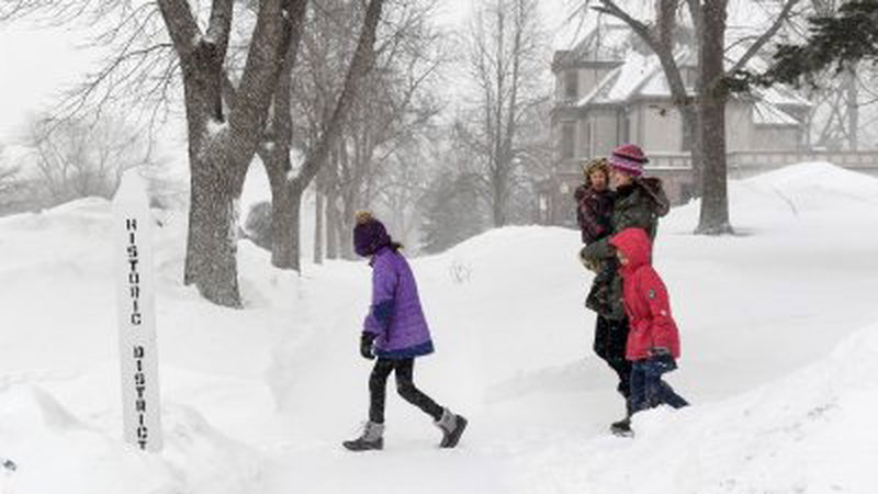 暴风雪当地时间周三席卷美国各地，在中西部的南达科他州苏瀑市，当地有一家人在大雪中行走。（图取自路透社）