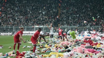 贝西克塔斯队球迷周日在伊斯坦布尔沃达丰体育场举行的比赛暂停期间，将毛绒玩具扔到球场，球员将玩具集中到场边。（图取自路透社）