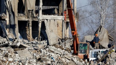 工人们当地时间周二清除一座被毁建筑物的残骸，据称这是一所职业学院，用作俄罗斯士兵的临时住所。（图取自路透社）