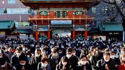 戴著口罩的日本民众于周三，也就是新年的第一个工作日在神田明神神社祈祷。神田明神神社是寻求好运和生意繁荣的信徒，经常参拜的地方。（图取自路透社）