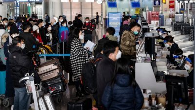中国周日起对新冠肺炎病毒感染实施“乙类乙管”，有序恢复中国公民出境旅游。图为当天在北京首都国际机场T3航站楼日本航空公司的值机柜台，旅客排队等待办理登机手续。（图取自中新社）