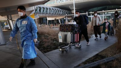 周四韩国仁川机场外，一名身穿防护服的军人领著中国旅客去做核酸检测。（路透社）