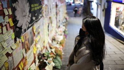 韩国梨泰院踩踏事件调查结果出炉，警方归咎于准备不足及缺乏合作。图为去年12月18日，一民众在事发地点的墙面上读著纸条上的悼词。（路透社）