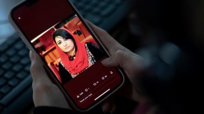 一名女子透过手机，看著阿富汗前女国会议员纳比扎达的照片。（图取自法新社）