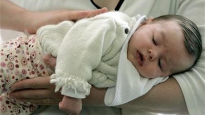 在法国西南部波尔多，一名3个月大的婴儿睡在她母亲的怀里。（图取自路透社档案照）