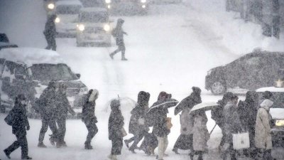行人在大雪中穿过北海道小樽市的街道。（图取自读卖新闻网）