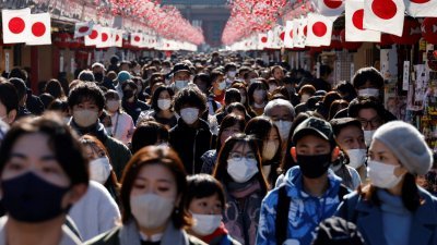 在日本东京浅草区通往浅草寺的仲见世街，戴著口罩的游客在新年装饰下走过。（图取自路透社）