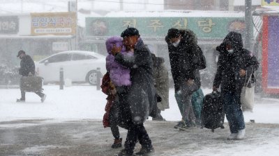 乘客周二冒著大雪，前往光州火车站。（图取自路透社）